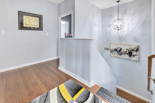 stairs featuring an inviting chandelier and hardwood / wood-style flooring