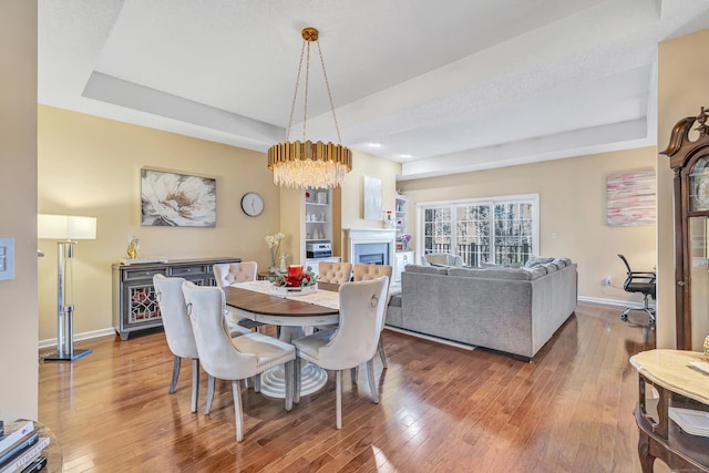 dining room featuring a chandelier, wood-type flooring, and a raised ceiling