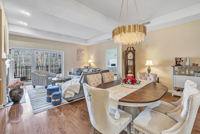 dining area featuring hardwood / wood-style floors, an inviting chandelier, and a tray ceiling