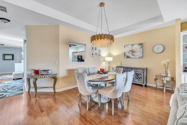 dining space with a tray ceiling and light hardwood / wood-style flooring