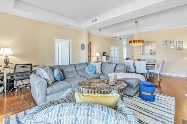 living room with a tray ceiling and wood-type flooring