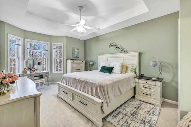 carpeted bedroom featuring a raised ceiling and ceiling fan