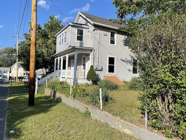 view of side of property with a porch and a lawn