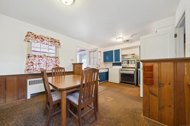 dining space featuring dark carpet, radiator heating unit, and wood walls