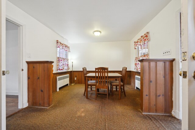 dining space featuring a wealth of natural light, radiator heating unit, and dark carpet