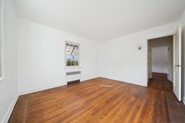 unfurnished living room with dark hardwood / wood-style floors and radiator