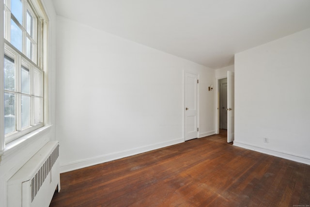 unfurnished room featuring dark wood-type flooring and radiator heating unit