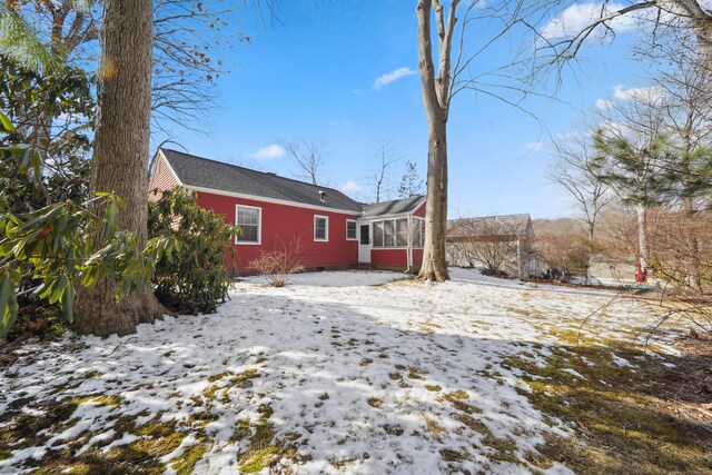 snow covered house featuring a sunroom