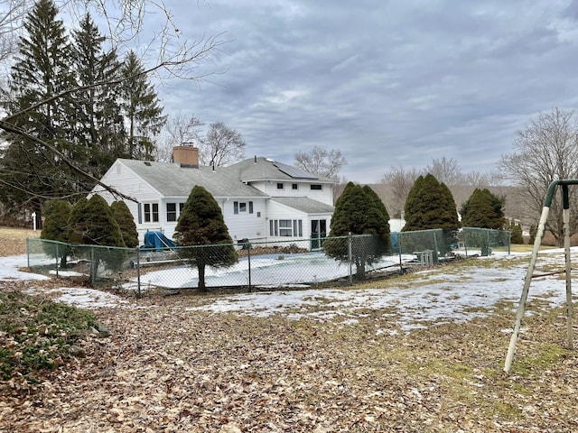 snow covered back of property featuring a chimney and fence