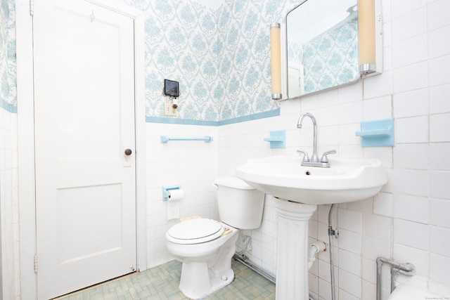 bathroom with tile patterned floors, toilet, and tile walls