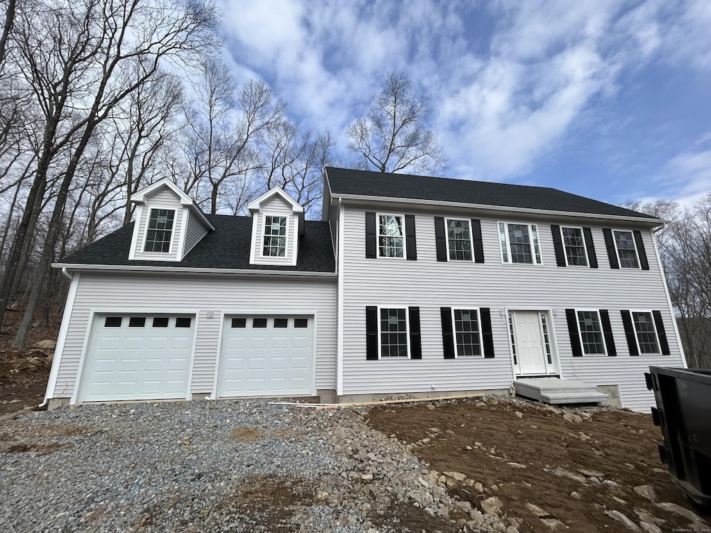 colonial inspired home with driveway, a shingled roof, and a garage