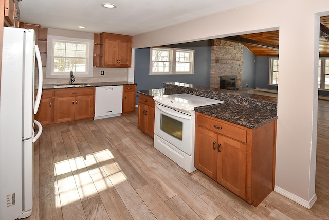 kitchen with sink, light wood-type flooring, beamed ceiling, white appliances, and dark stone counters