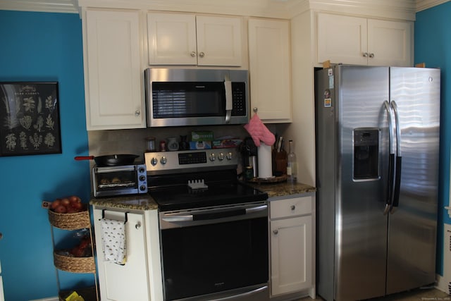 kitchen featuring white cabinetry, tasteful backsplash, stainless steel appliances, and dark stone countertops