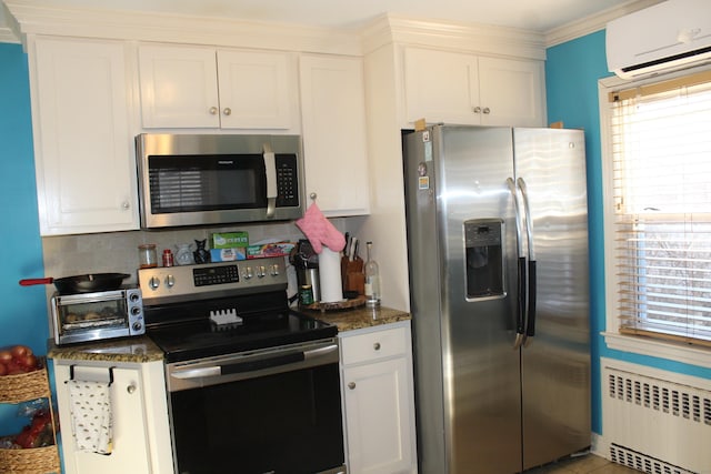 kitchen featuring white cabinetry, appliances with stainless steel finishes, a wall unit AC, and radiator heating unit