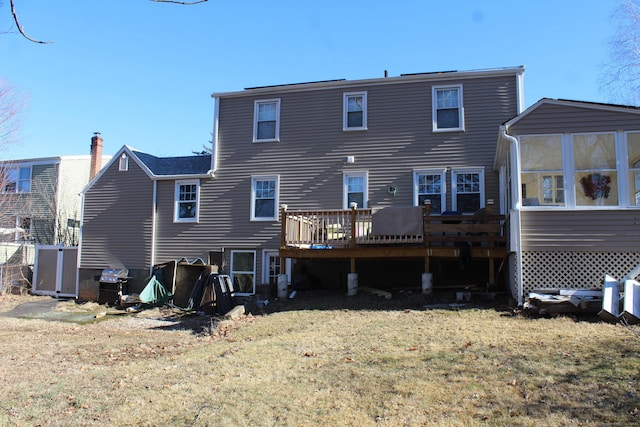 rear view of property featuring a yard, a deck, and a sunroom