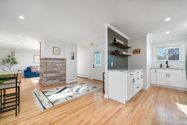 kitchen featuring white cabinets, a baseboard heating unit, light stone counters, crown molding, and light hardwood / wood-style flooring