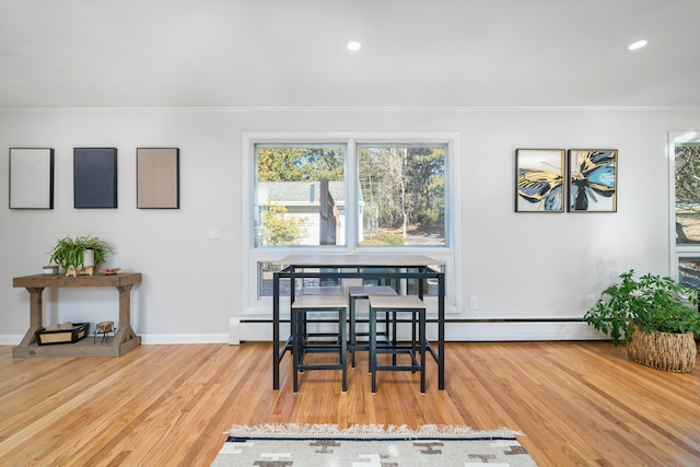 dining area featuring a baseboard radiator, ornamental molding, and light hardwood / wood-style floors