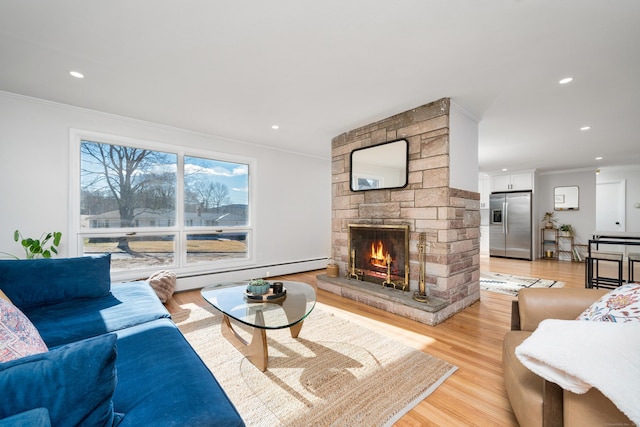 living room featuring a stone fireplace, light hardwood / wood-style flooring, ornamental molding, and baseboard heating