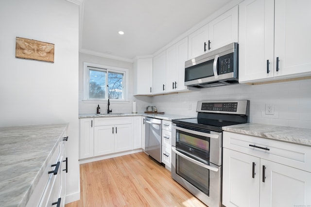 kitchen with light stone counters, appliances with stainless steel finishes, sink, and white cabinets