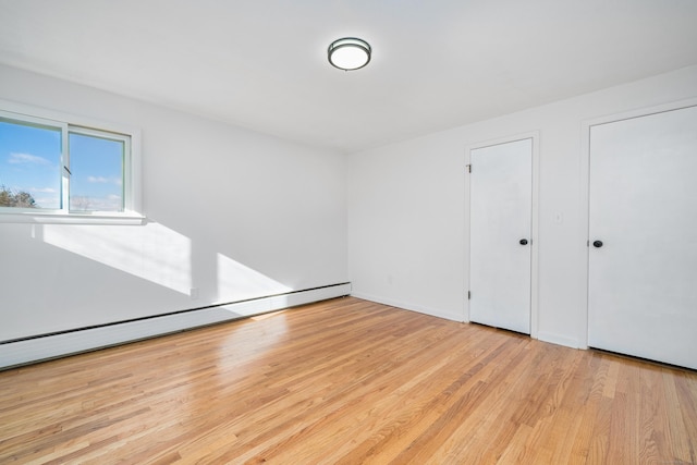 unfurnished bedroom featuring a baseboard radiator and light hardwood / wood-style floors