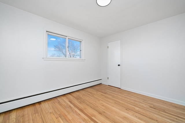 empty room with baseboard heating and light hardwood / wood-style floors