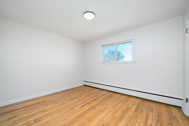 empty room with baseboard heating and light hardwood / wood-style flooring