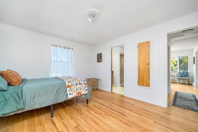 bedroom with light wood-type flooring and baseboard heating