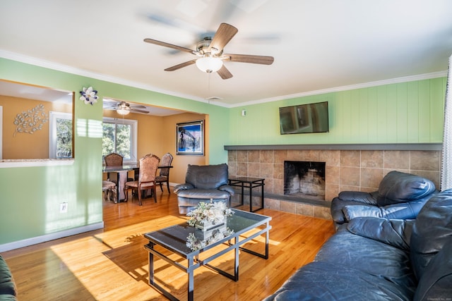 living room with hardwood / wood-style flooring, ornamental molding, and a tile fireplace