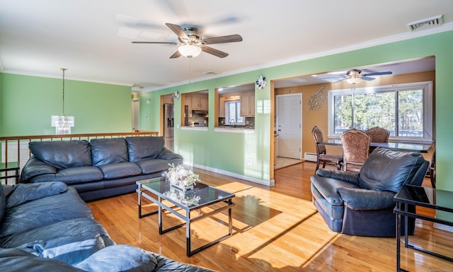 living room featuring ornamental molding, ceiling fan with notable chandelier, and light wood-type flooring