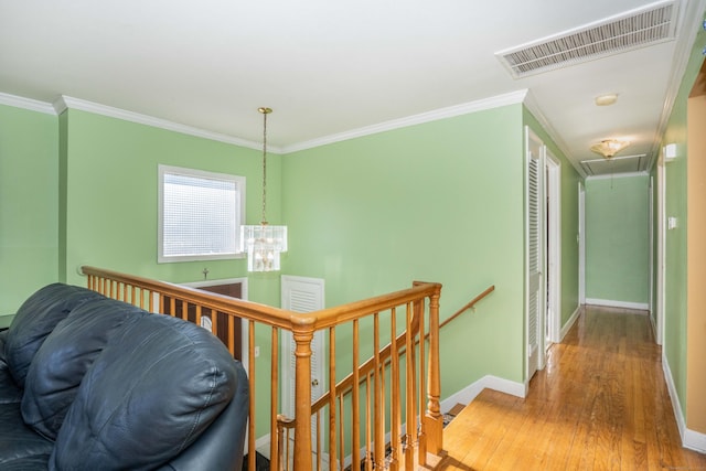 hall featuring crown molding, an inviting chandelier, and hardwood / wood-style flooring