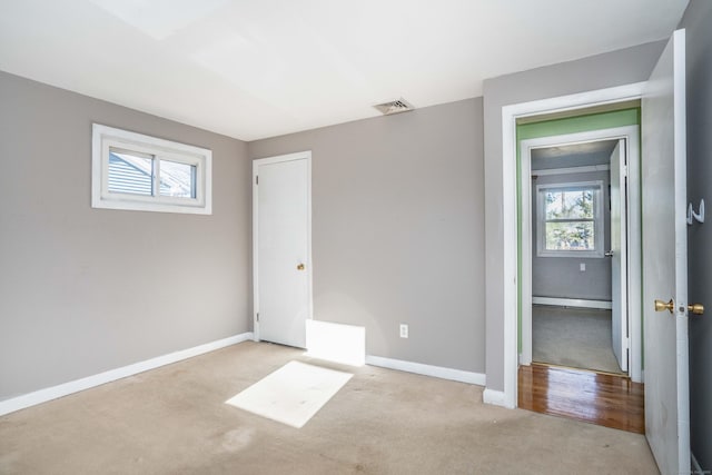 unfurnished bedroom featuring a baseboard heating unit and light colored carpet