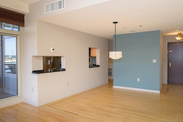 unfurnished living room featuring light wood-style floors, visible vents, and baseboards