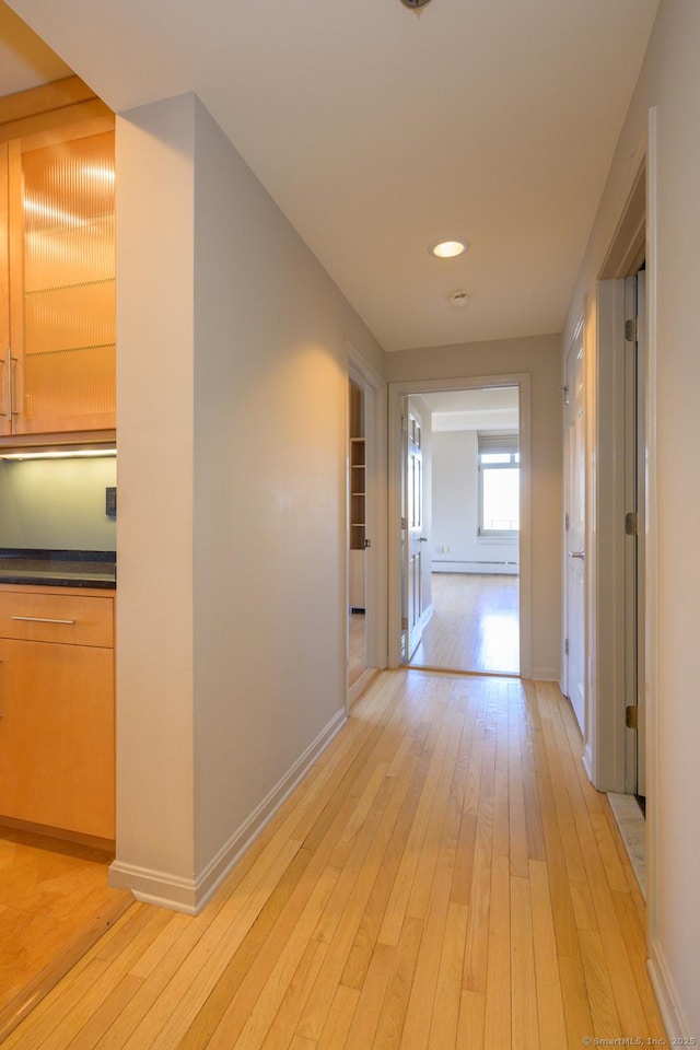 corridor with light wood-type flooring and baseboards