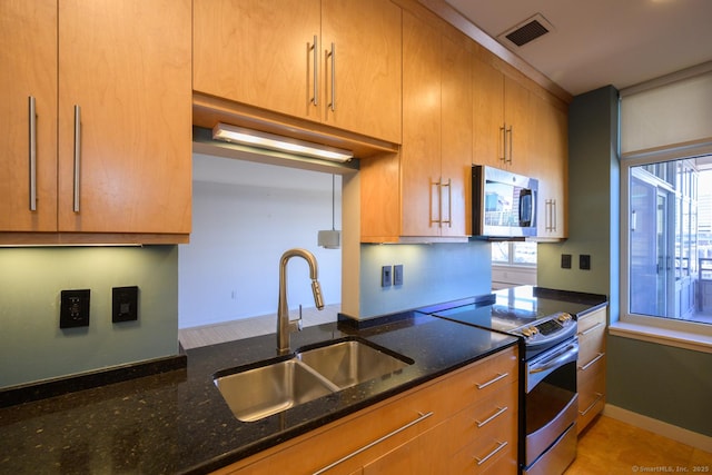 kitchen featuring dark stone countertops, baseboards, visible vents, a sink, and stainless steel appliances