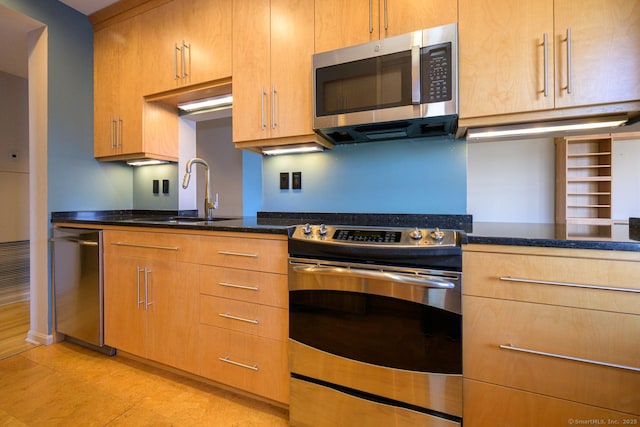 kitchen with appliances with stainless steel finishes, dark stone counters, and a sink