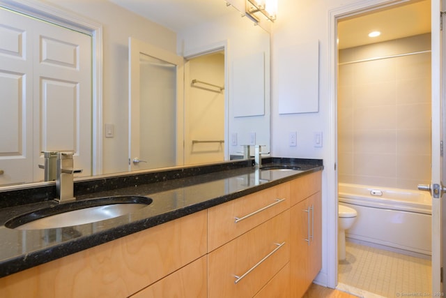 full bathroom with double vanity, toilet, bathtub / shower combination, and a sink