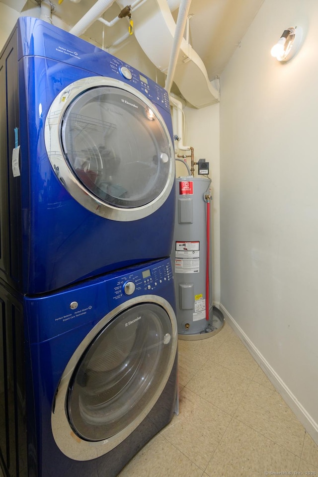 washroom with tile patterned floors, electric water heater, stacked washer / dryer, baseboards, and laundry area