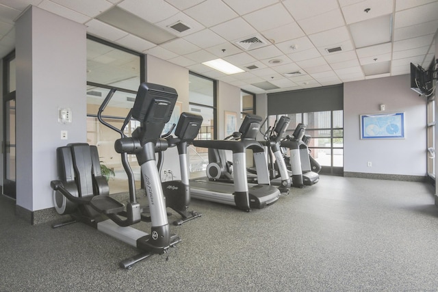 exercise room with visible vents, a paneled ceiling, and baseboards