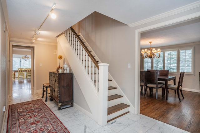 stairway with crown molding, track lighting, and a chandelier