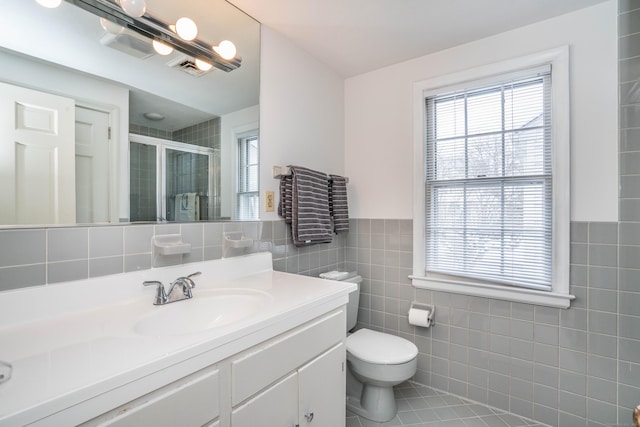 bathroom featuring tile walls, vanity, an enclosed shower, toilet, and tile patterned floors