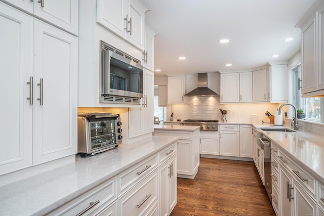 kitchen featuring sink, stainless steel appliances, dark hardwood / wood-style floors, white cabinets, and wall chimney exhaust hood