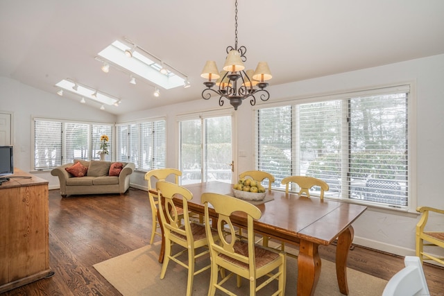 dining area featuring dark hardwood / wood-style floors, lofted ceiling with skylight, and an inviting chandelier