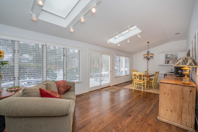 sunroom / solarium with vaulted ceiling with skylight, a chandelier, and rail lighting