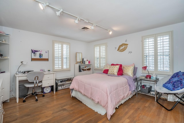 bedroom with rail lighting and hardwood / wood-style floors