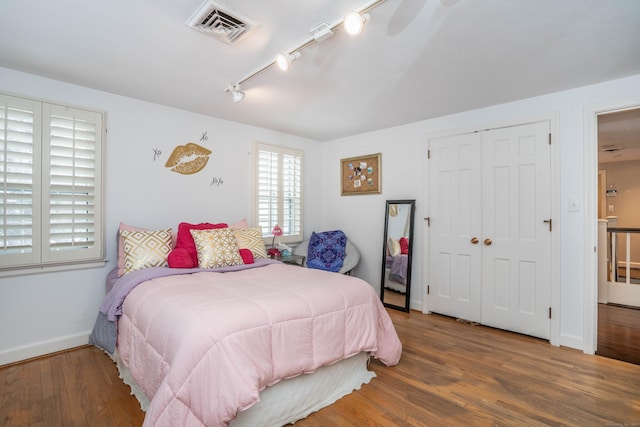 bedroom with rail lighting, dark wood-type flooring, and a closet