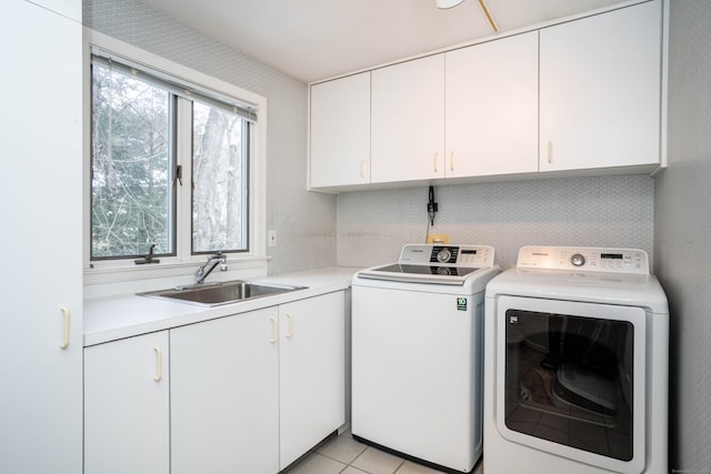 clothes washing area featuring cabinets, sink, light tile patterned floors, and independent washer and dryer