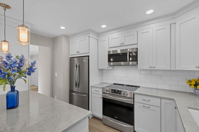 kitchen featuring white cabinetry, light stone counters, pendant lighting, and stainless steel appliances