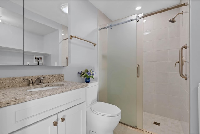 bathroom with a shower with door, vanity, and toilet