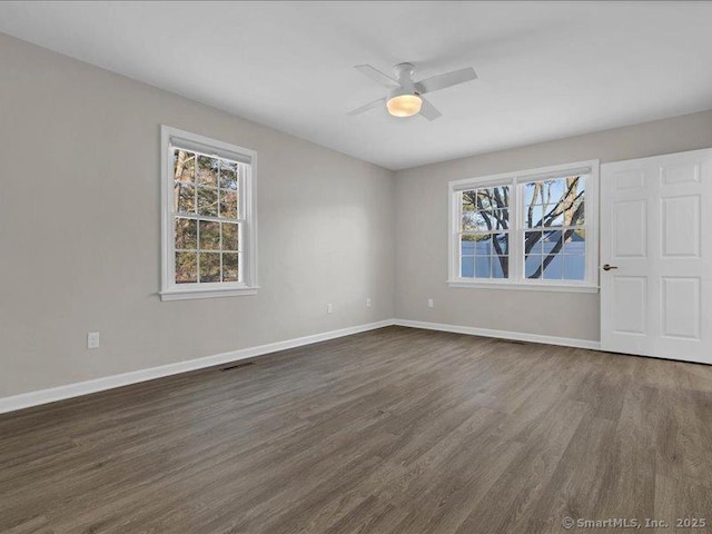 unfurnished room featuring dark wood-type flooring, a wealth of natural light, and ceiling fan