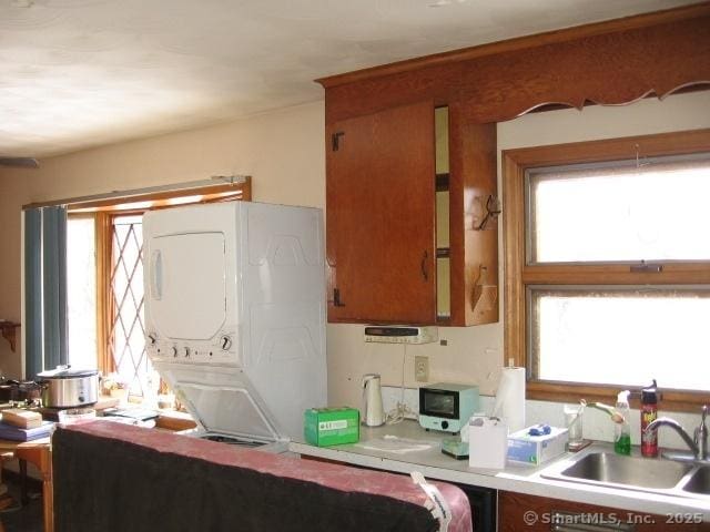 kitchen featuring stacked washer / drying machine and sink